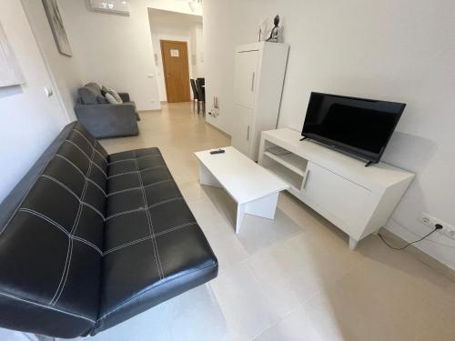 a living room with a black leather couch and a tv at Royal Suites Estepona by Croma in Estepona