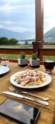 a plate of food sitting on a table with a cell phone at The Lake Breeze Bay in Plav