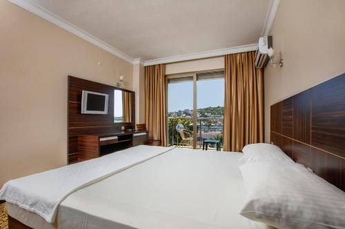 a bedroom with a bed and a desk and a television at Suena hotel Çeşme in Çeşme