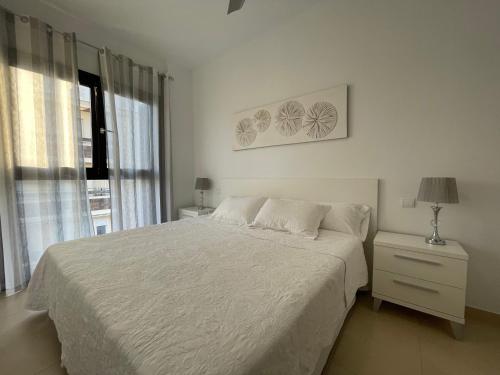 a white bedroom with a bed and a window at Royal Suites Estepona by Croma in Estepona