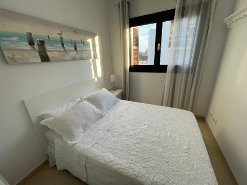a white bed in a bedroom with a window at Royal Suites Estepona by Croma in Estepona