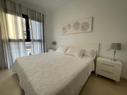 a white bedroom with a bed and a window at Royal Suites Estepona by Croma in Estepona