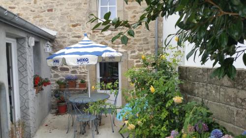 une table et des chaises sous un parasol devant un bâtiment dans l'établissement Menhir douarnenez, à Douarnenez