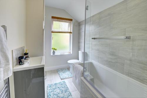 a white bathroom with a tub and a sink at The Quirky Cottage in Leicester