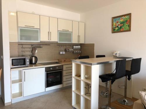 a kitchen with white cabinets and a table with chairs at Apartment Marina in Bar