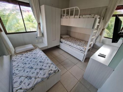 a bedroom with two bunk beds and a desk at Apartamento mobiliado Beach Place Porto das Dunas in Prainha