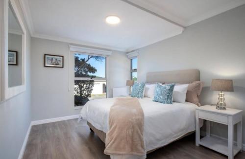 a bedroom with a large white bed and a window at 29@Whale Rock Estate in Hermanus