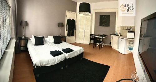 a bedroom with a bed and a desk and a kitchen at El Sol Zandvoort in Zandvoort