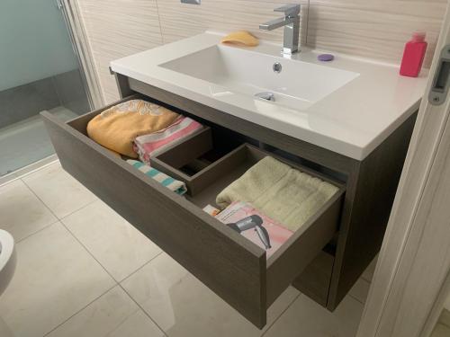 een badkamer met een wastafel en een lade met handdoeken bij Affittacamere EROI in Verbania