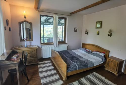 a bedroom with a bed and a desk and a mirror at vila zia in Corbeni