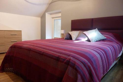 um quarto com uma cama grande e um cobertor vermelho em Gite de Bossican em Montmartin-le-Haut