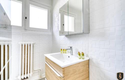 La salle de bains blanche est pourvue d'un lavabo et d'un miroir. dans l'établissement Grande maison 160 m2 6 chambres à Caen, à Caen