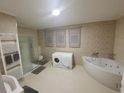 a bathroom with a washing machine and a bath tub at Apartman Libertas in Posušje