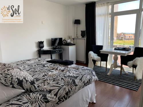 a bedroom with a bed and a desk and a window at El Sol Zandvoort 2 in Zandvoort