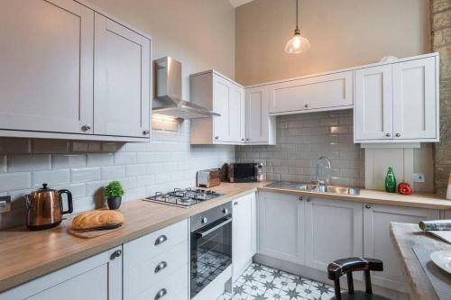 a kitchen with white cabinets and a stove top oven at The Oldgate in Morpeth