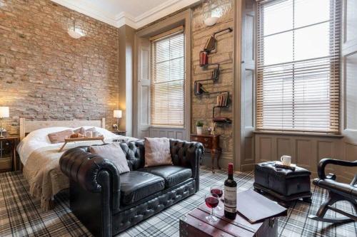 a bedroom with a couch and a brick wall at The Oldgate in Morpeth