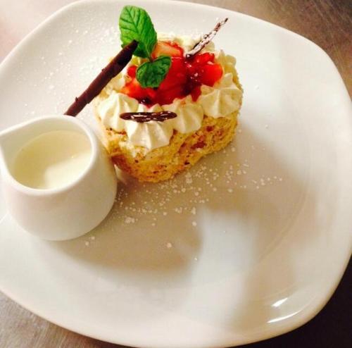 a white plate with a piece of cake with whipped cream at The Fairburn Hotel in Mauchline