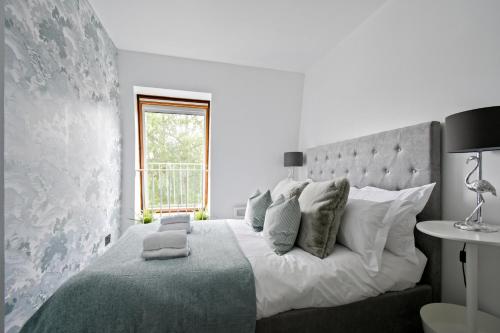 a white bedroom with a large bed and a window at Stylish One Bed Apartment Near Cotswolds RAF in Carterton