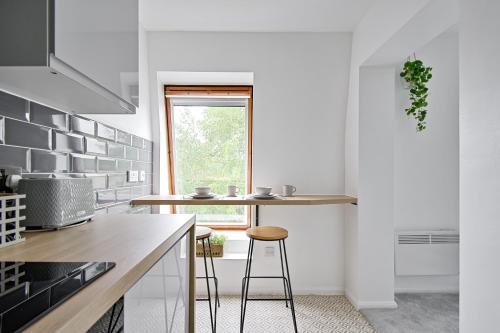 a kitchen with white walls and a counter with stools at Stylish One Bed Apartment Near Cotswolds RAF in Carterton