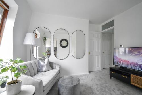 a living room with a white couch and three mirrors at Stylish One Bed Apartment Near Cotswolds RAF in Carterton