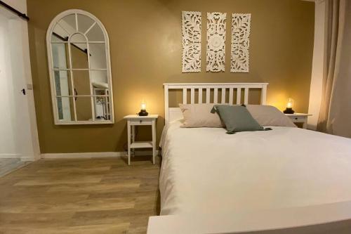 a bedroom with a white bed with two tables and a mirror at Craftsman's House in Nordeste