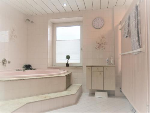 ゼンフテンベルクにあるPenthouse Wolkenstein großzügige Maisonette auf 155 qm mit Whirlpool, Klima & Kaminのバスルーム(バスタブ、シンク、時計付)