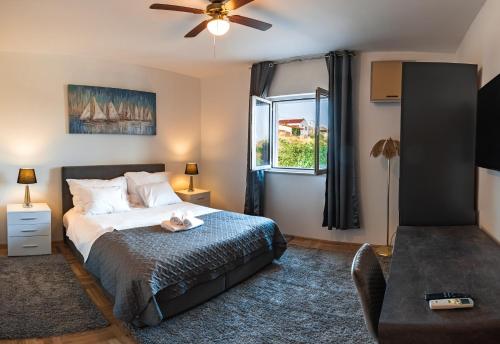 a bedroom with a bed with a ceiling fan and a window at Seaview Villa Summer with private pool & garden in Rtina