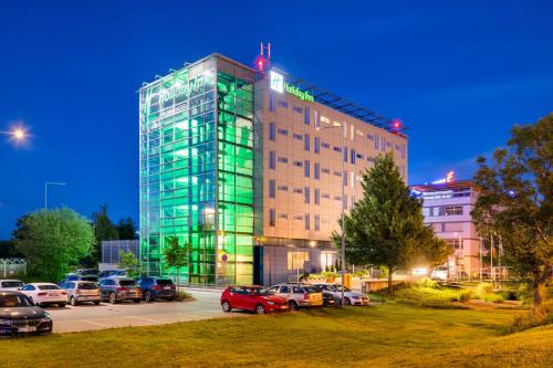 a building with cars parked in a parking lot at Holiday Inn Prague Airport, an IHG Hotel in Prague