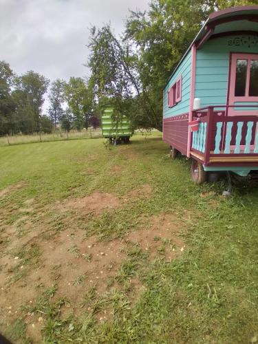 uma carruagem azul e vermelha estacionada num campo em Roulotte verte em Pouilly-sur-Vingeanne