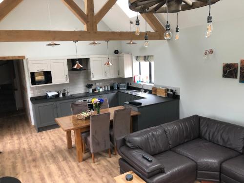 a kitchen and living room with a couch and a table at Newly Converted Luxury Barn With Private Hot Tub in Bodfari