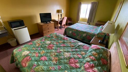 a hotel room with two beds and a television at Sunset Inn-Rolla in Rolla