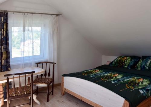 Un dormitorio con una cama y una mesa y una ventana. en W Ziołowym Ogrodzie - pokoje z dostępną kuchnią, apartament, en Kudowa-Zdrój