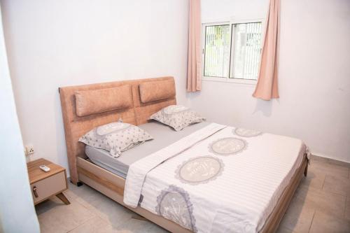 um quarto com uma cama com lençóis brancos e uma janela em guest mtsangamouji F3 em Mtsamgamouji