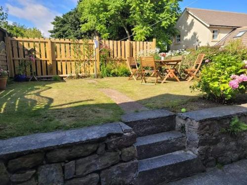 a backyard with a stone wall and a table and chairs at Seahouses cottage in Seahouses