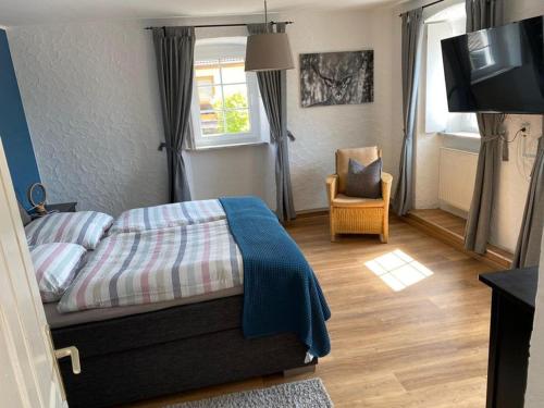 um quarto com uma cama, uma cadeira e uma televisão em Am Osterberg em Büdesheim