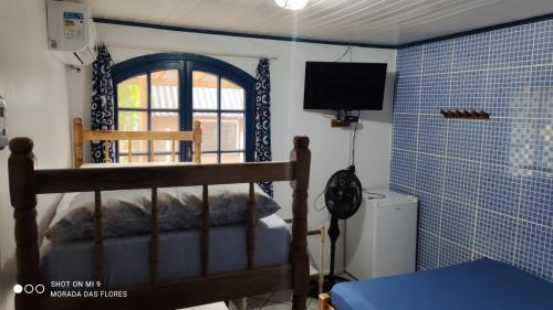 a bedroom with a bed and a window and a television at Pousada Morada das Flores in Ilha do Mel
