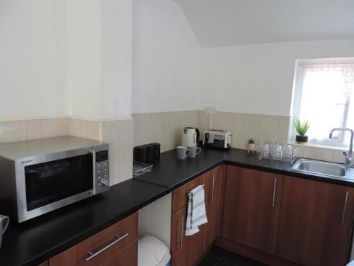 a kitchen with a microwave and a sink at Palmerston House, 5 Bed sleeps 12 in Spon End