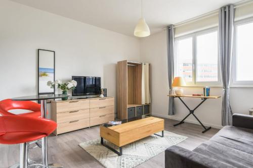 een woonkamer met een bank en een rode stoel bij Charming studio 15 min from Lille in Marcq-en-Baroeul - Welkeys in Marcq-en-Baroeul
