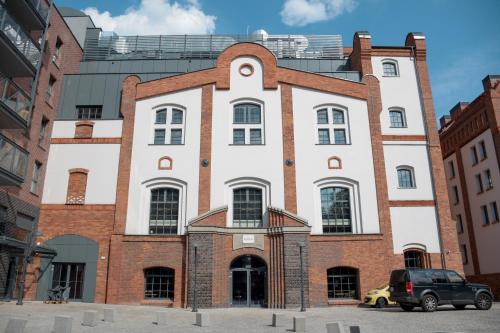 budynek z samochodem zaparkowanym przed nim w obiekcie Apartamenty Nowy Browar Gdański w Gdańsku