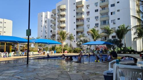 a swimming pool with umbrellas and people in a hotel at Lagoa Quente Flat Service in Caldas Novas
