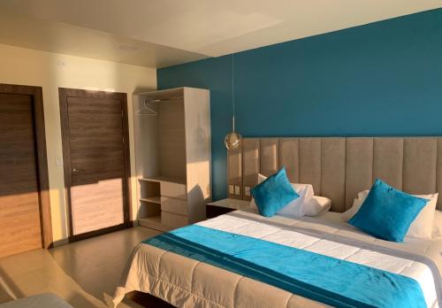 a bedroom with a large bed with blue walls at Hotel La Laguna Galapagos in Puerto Villamil