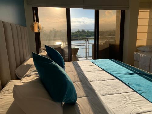 a bedroom with a bed with pillows and a large window at Hotel La Laguna Galapagos in Puerto Villamil