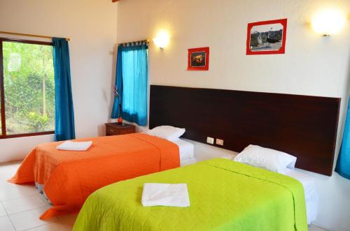 a hotel room with two beds with orange and green sheets at Piedras Blancas Lodge in Puerto Ayora