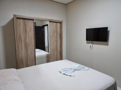 um quarto com 2 camas, uma televisão e um espelho. em Flat Genoveva em Tangara da Serra