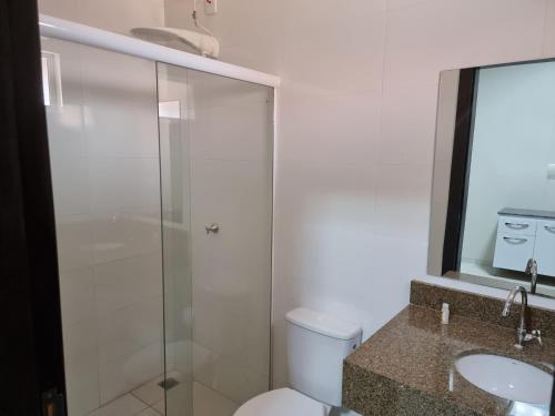 a bathroom with a shower and a toilet and a sink at Flat Genoveva in Tangara da Serra