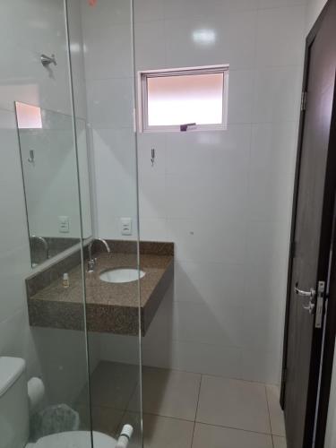 a bathroom with a sink and a glass shower at Flat Genoveva in Tangara da Serra