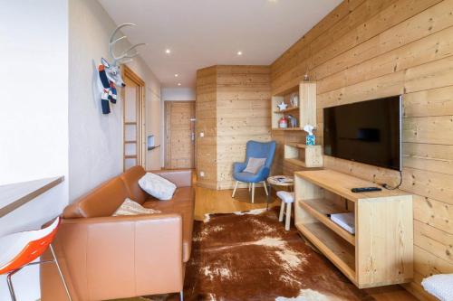 ein Wohnzimmer mit einem Sofa und einem TV in der Unterkunft Cosy flat with terrace in Huez - Welkeys in Huez