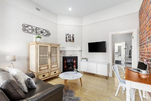 a living room with a couch and a table at Boutique Heritage Studios On Ryrie Geelong CBD Opposite hospital in Geelong