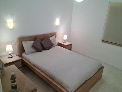 a bedroom with a bed with two lamps on two tables at SolTroia - Casa do Pinheiro in Troia
