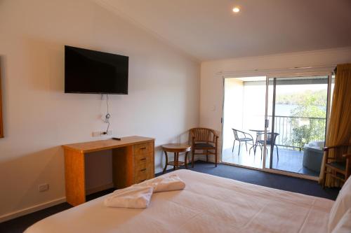 a bedroom with a bed and a television and a balcony at De Lago Resort On Lake Bennett in Lake Bennett